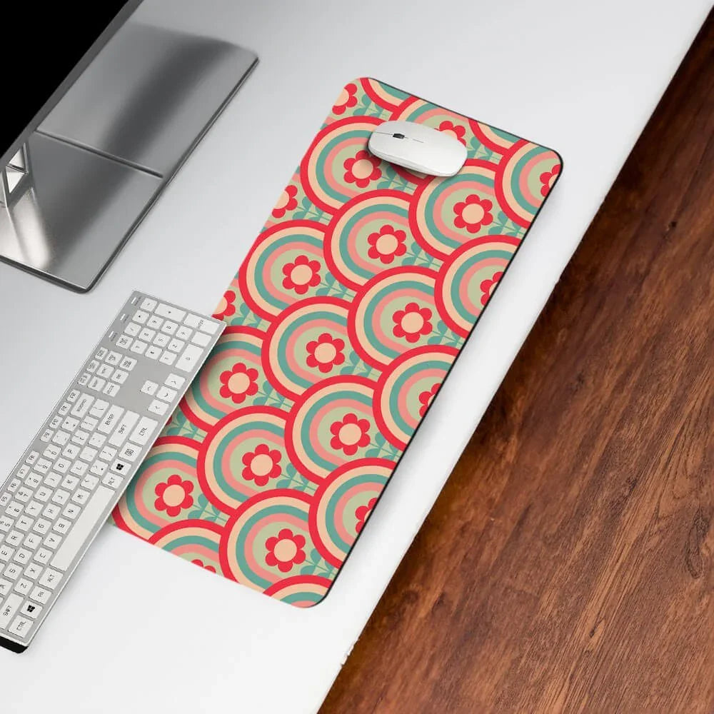 Colorful floral patterned desk mat with computer mouse on white desk beside keyboard.