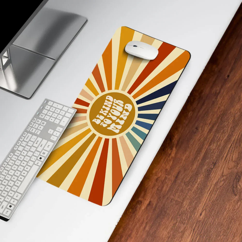 Retro desk mat with 'Be Kind to Your Mind' text, colorful sunburst pattern, on office desk