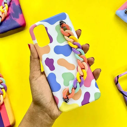 Colorful abstract pattern phone case with pastel chain handle, held in hand on yellow background
