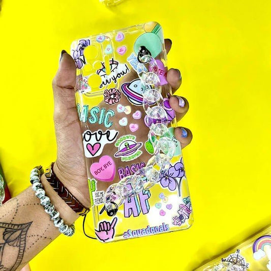 Colorful chain and charm phone case with stickers, held in hand on a yellow background