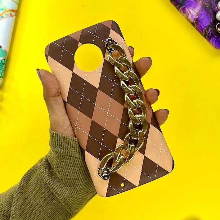 Brown checkered phone case with gold chain handle, held in hand on yellow background