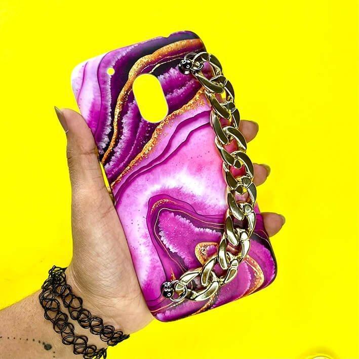 Purple marble design phone case with gold chain charm held against yellow background
