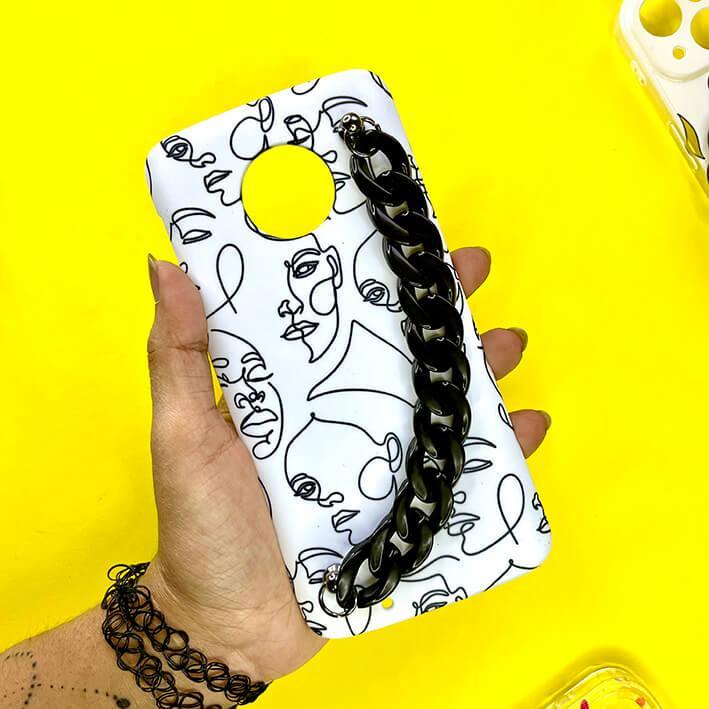 White phone case with abstract face line art and black chain handle, held against yellow background