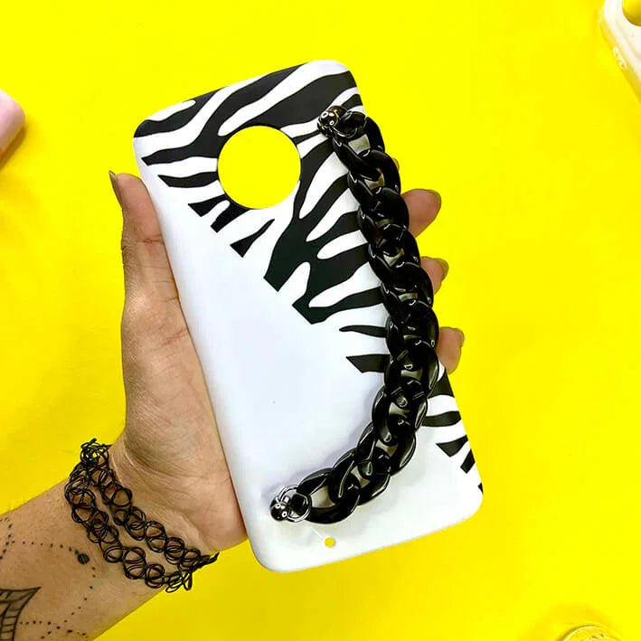 Zebra print phone case with black chain handle, held in hand on yellow background