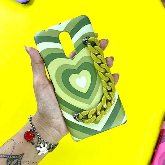 Green heart patterned phone case with matching chain charm held in hand against yellow background