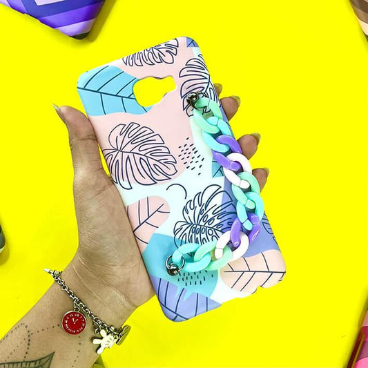 Pastel leaf print phone case with colorful chain charm, held in hand on yellow background