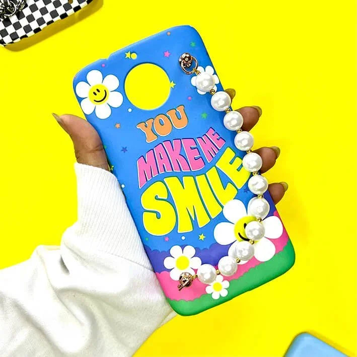 Colorful phone case with 'You Make Me Smile' text, daisies, smiley faces, and pearl chain charm