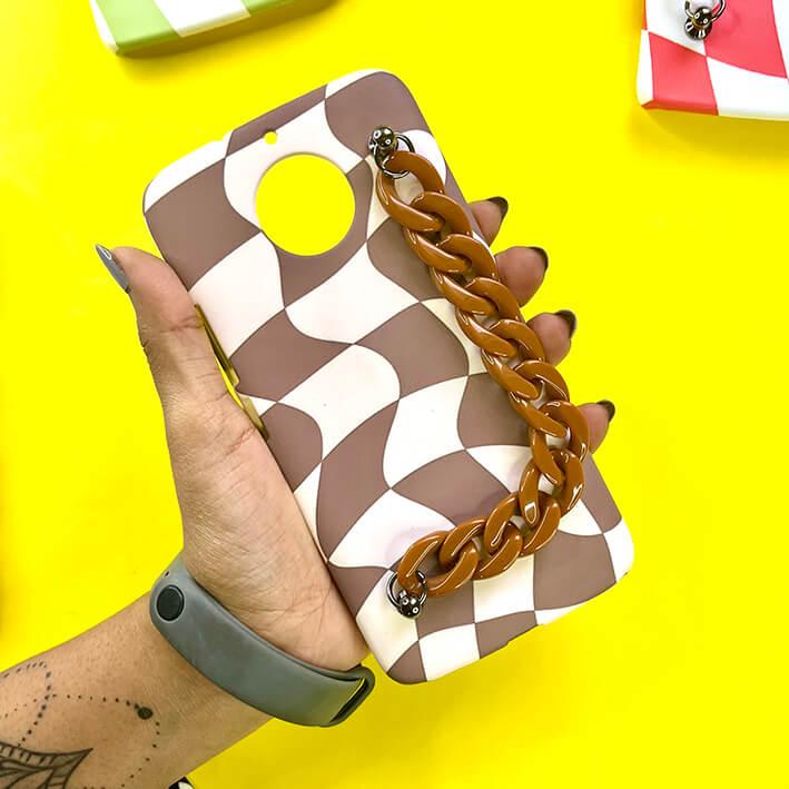 Brown and white wavy checker chain phone case with chunky chain handle, held in hand