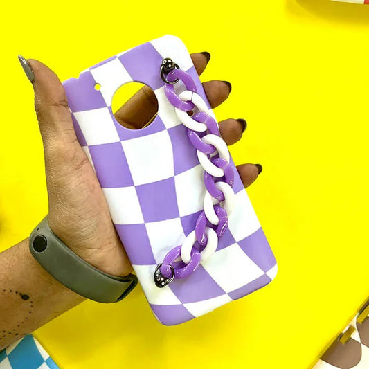 Hand holding purple and white checkered phone case with matching chain charm on yellow background