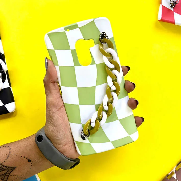 Green and white checkered phone case with chain handle, held in hand, stylish cover design