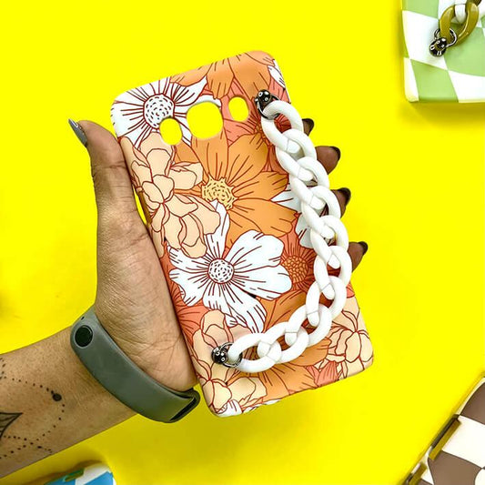Floral phone case with white chain charm held in hand on bright yellow background