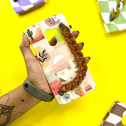Hand holding abstract art phone case with brown chain grip on yellow background
