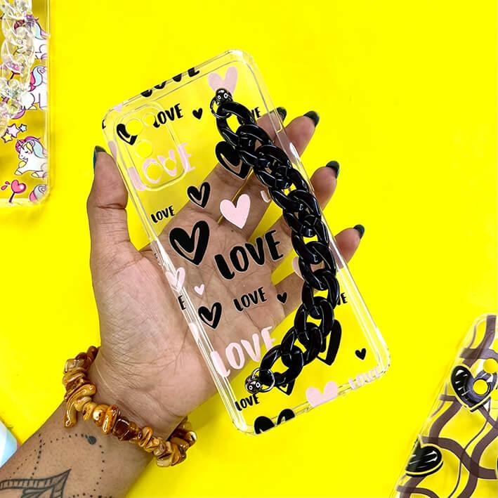 Clear phone case with black chain, heart designs, and 'love' text, held on yellow background