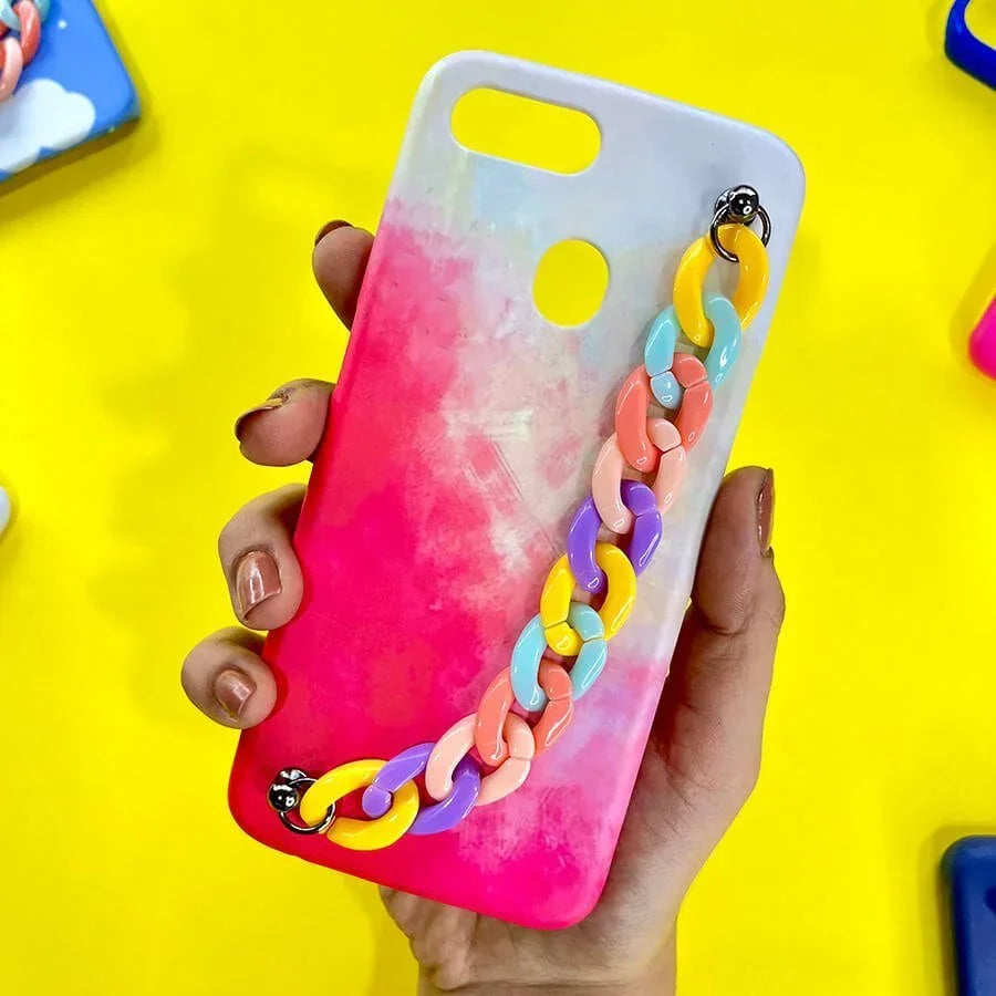 Hand holding a pink and white gradient phone case with colorful chain charm on yellow background