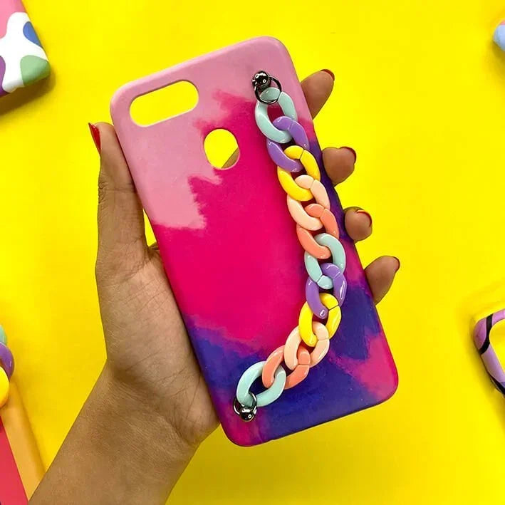 Hand holding pink and purple phone case with colorful chain charm on yellow background