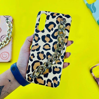 Leopard print phone case with gold chain charm held in hand on yellow background