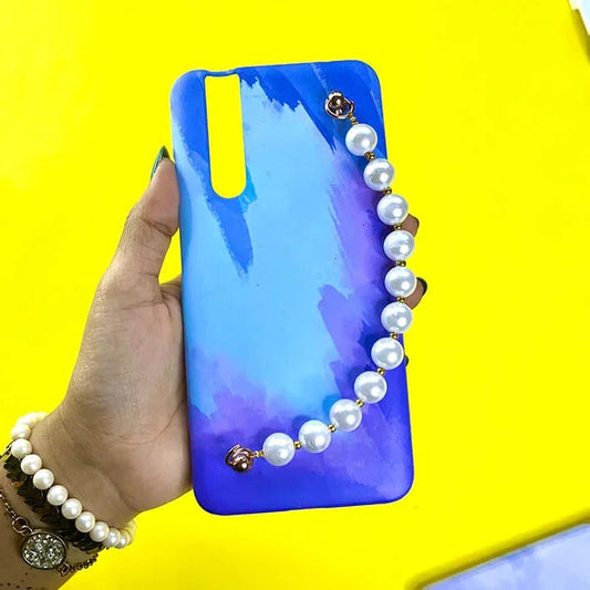 Blue gradient phone case with pearl chain charm, held in hand on yellow background
