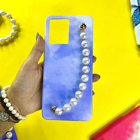 Hand holding blue gradient phone case with pearl chain charm, stylish accessory background.