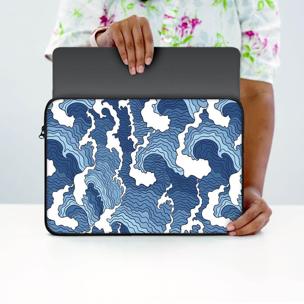 Person holding blue and white abstract patterned laptop sleeve on table