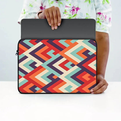 Person holding a laptop sleeve with colorful geometric pattern on a white table