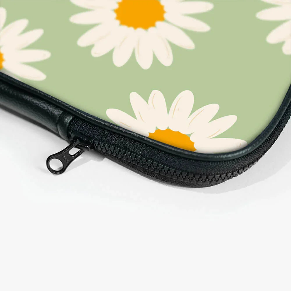 Closeup of a floral laptop sleeve zipper, green background with white daisy print
