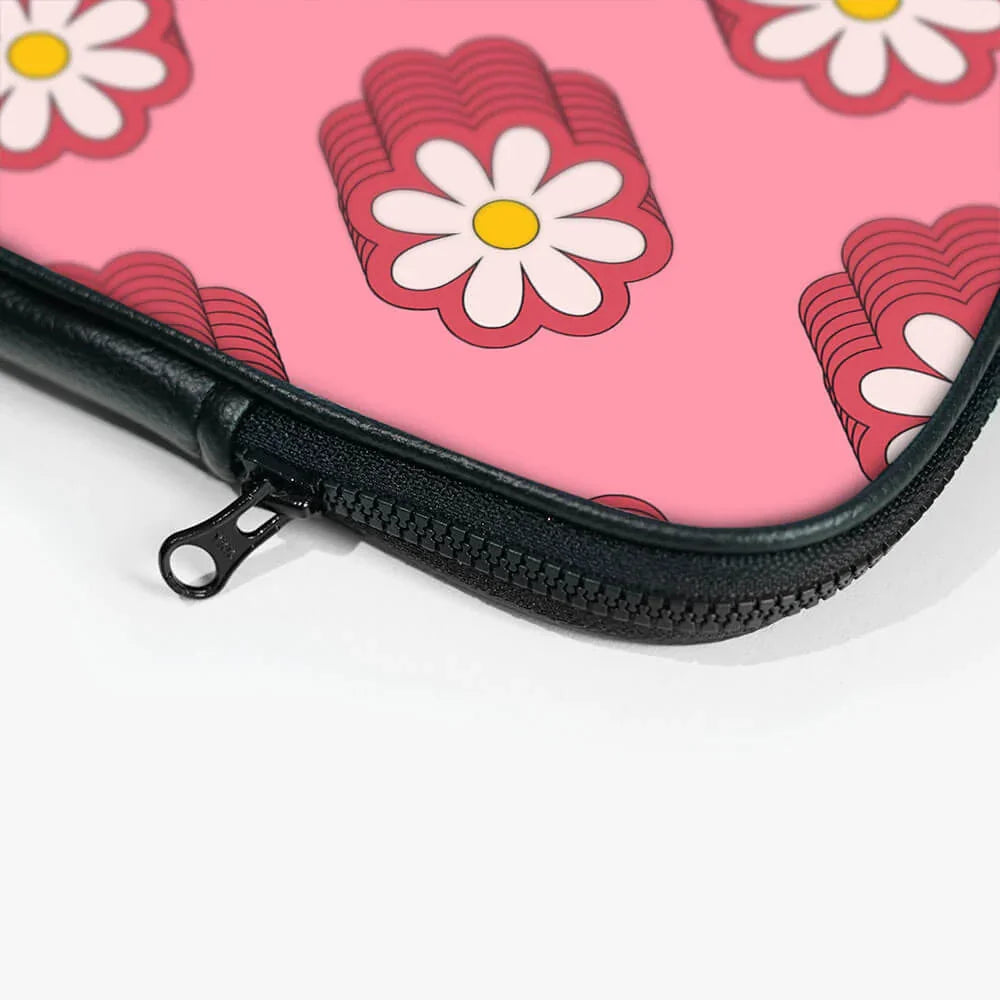 Pink laptop sleeve with white daisy flower pattern and black zipper close-up