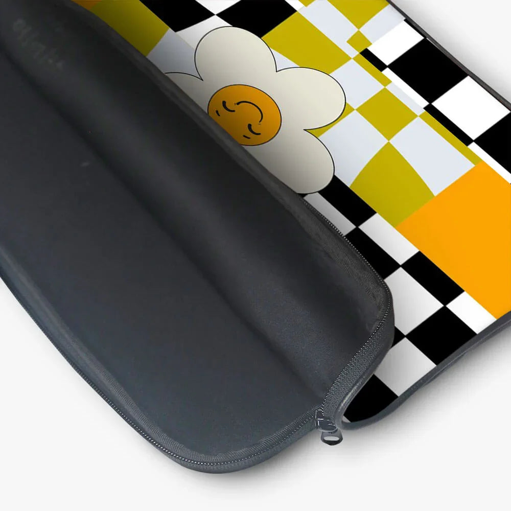 Black laptop sleeve with yellow, white, and black checkerboard pattern and a smiling flower design