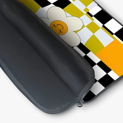 Black laptop sleeve with yellow, white, and black checkerboard pattern and a smiling flower design
