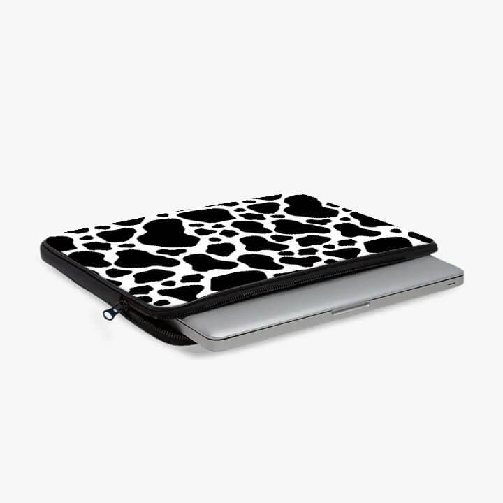 13-inch laptop sleeve with black and white cow print design, partially unzipped