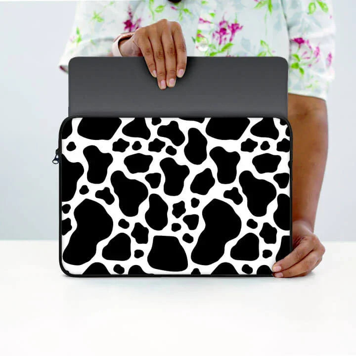 Person holding laptop in black and white cow print 13-inch laptop sleeve with zip pouch