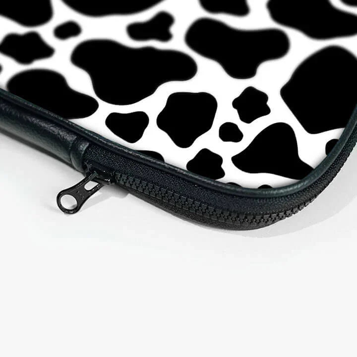 Black and white cow print laptop sleeve with zipper close-up