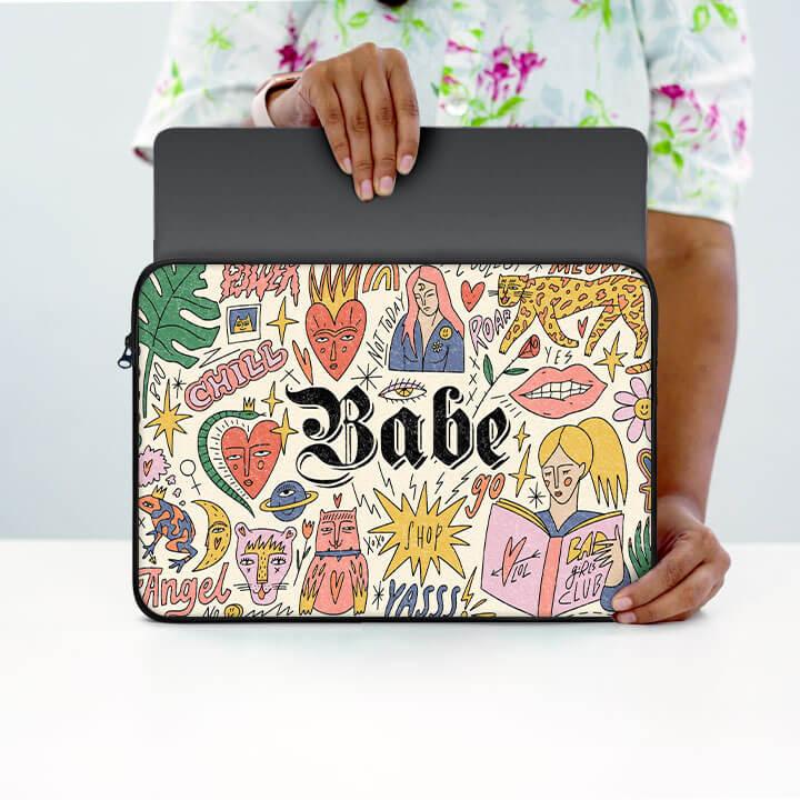 Colorful 13-inch laptop sleeve with doodle art and 'Babe' text, held by person in floral shirt