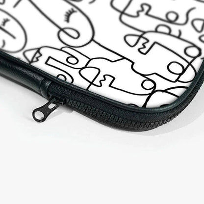 Close-up of a 13-inch laptop sleeve with abstract line art faces and a black zip pouch