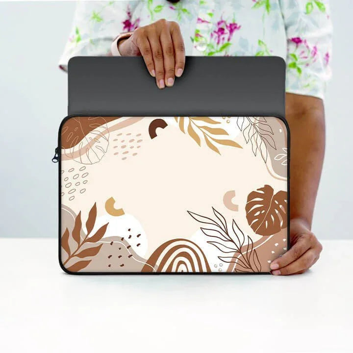 Person holding 13-inch laptop sleeve with abstract brown leaf design on white background