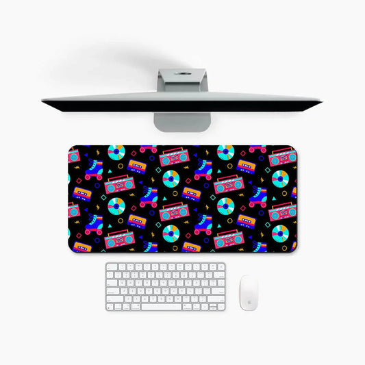 Retro desk mat with colorful cassette, boombox, CD, and roller skate pattern on a desk setup.