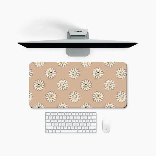 Beige desk mat with smiling daisy pattern, computer monitor, keyboard, and mouse on white desk