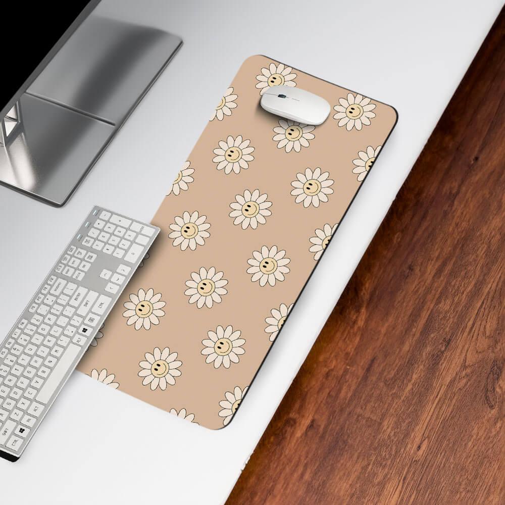 Beige desk mat with smiling daisy pattern, computer mouse, and keyboard on white desk