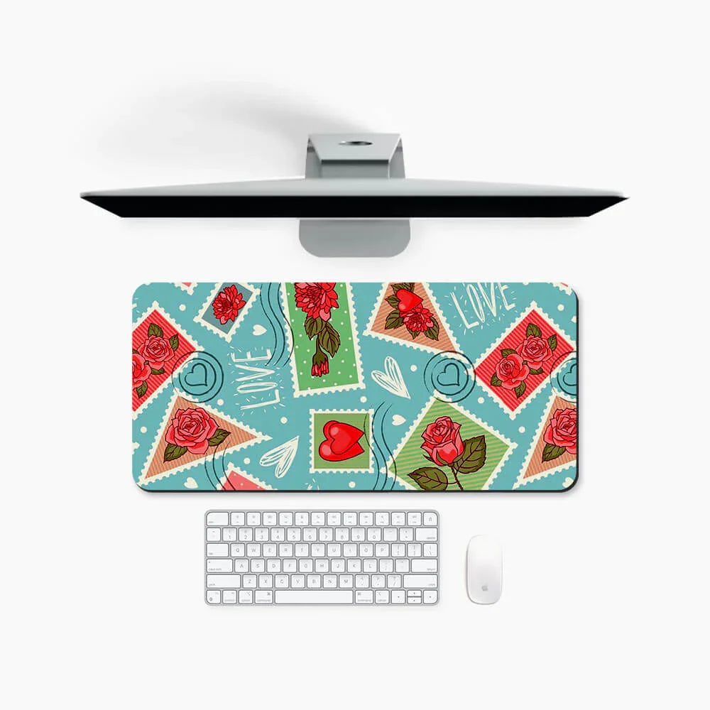 Colorful desk mat with rose and heart stamp designs on a workspace with monitor, keyboard, and mouse