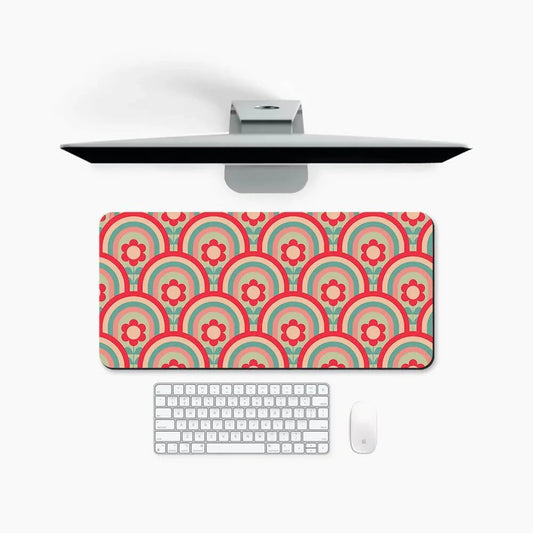 Colorful desk mat with retro floral and rainbow pattern under computer, keyboard, and mouse