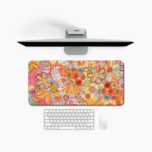 Floral patterned desk mat with orange and yellow colors, under keyboard and monitor