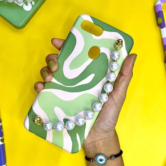 Green and white wavy pattern phone case with pearl chain charm held in hand on yellow background