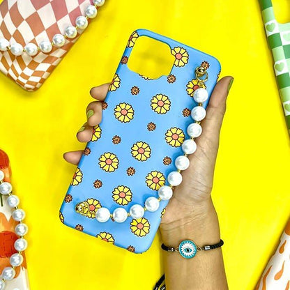 Blue floral phone case with daisy pattern and pearl chain charm, held in hand on yellow background