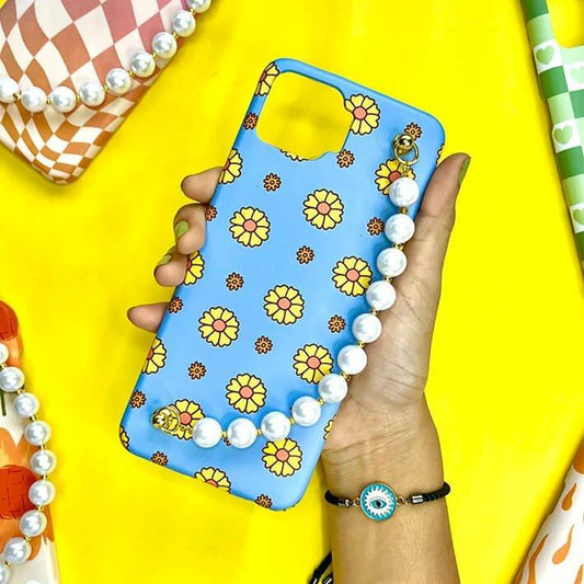 Blue floral phone case with daisy pattern and pearl chain charm, held in hand on yellow background
