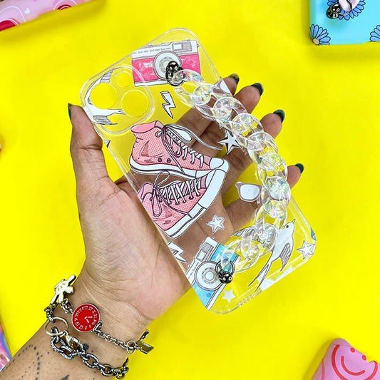 Clear phone case with pink sneakers, camera, and charm chain, held against yellow background