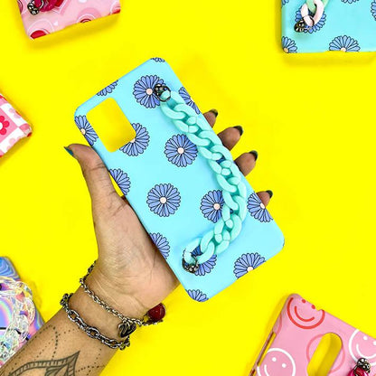 Blue phone case with purple daisy pattern and teal chain charm held in hand on yellow background