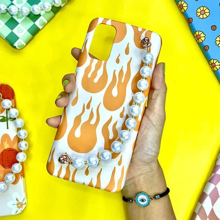 Orange flame phone case with pearl chain charm, held on a yellow background