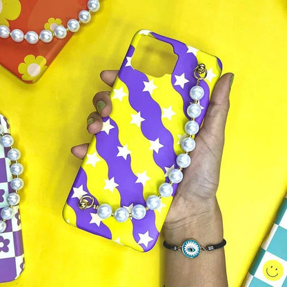 Yellow and purple star pattern phone case with pearl chain charm, held in hand on yellow background