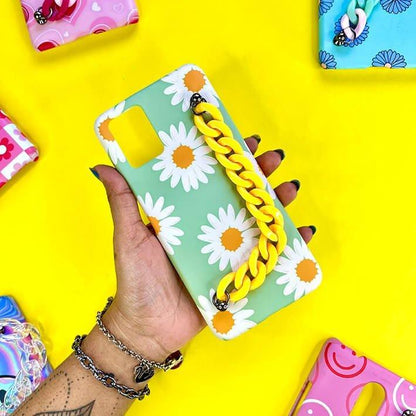 Green daisy floral phone case with yellow chain charm held by hand on yellow background