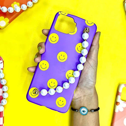 Purple phone case with yellow smiley faces and pearl chain held in hand on yellow background
