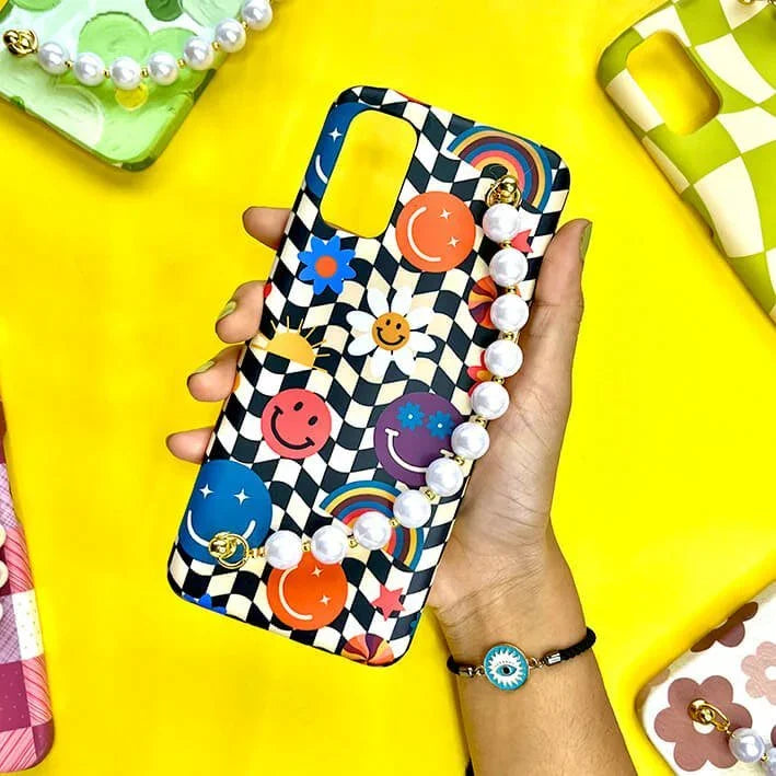 Colorful chain phone case with chequered pattern, smiley faces, rainbows, pearls held in hand